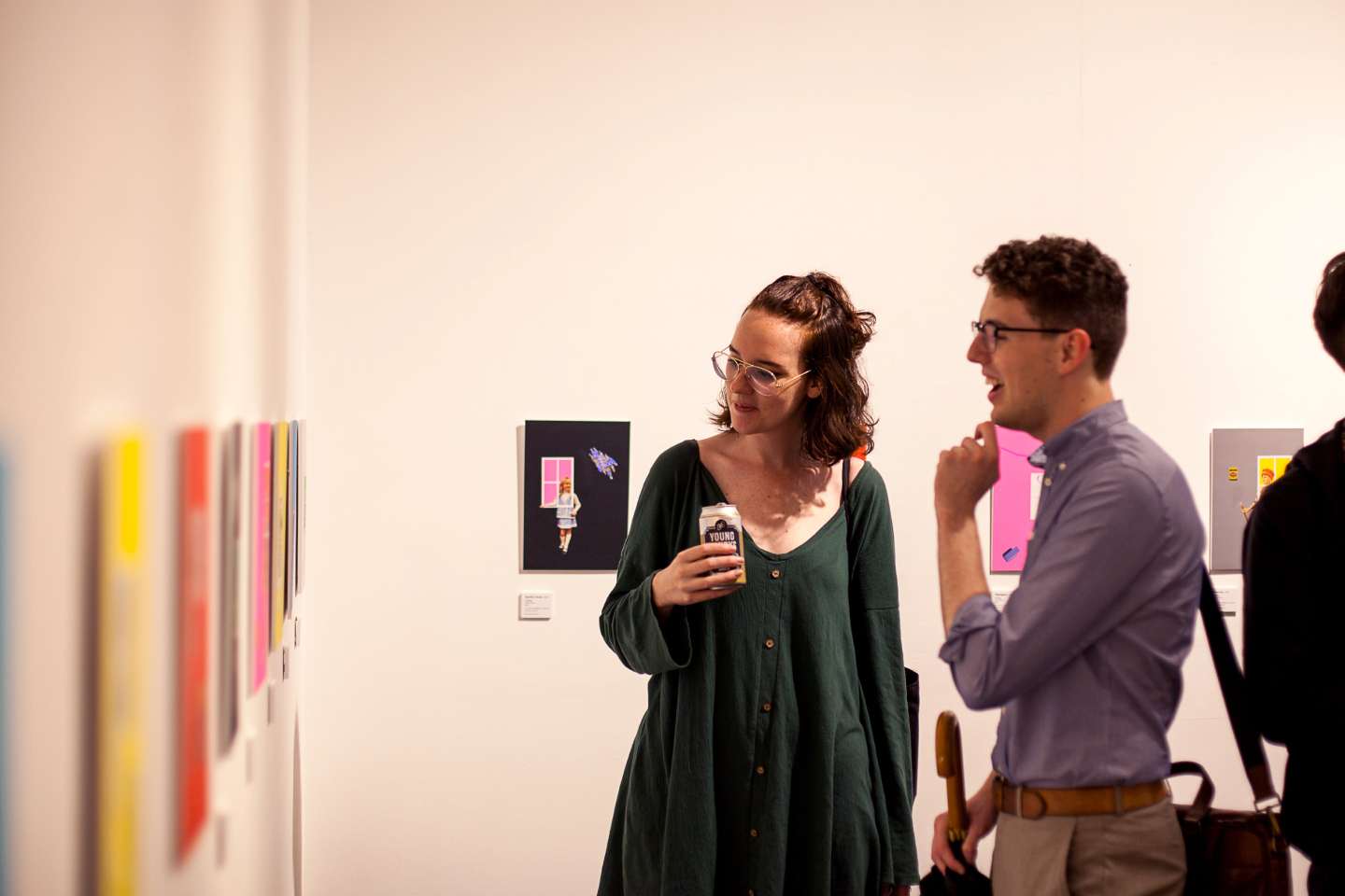 Two people in a gallery look at the exhibition on the walls.