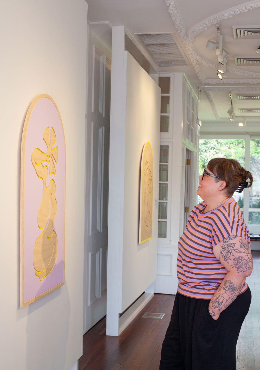 Woman standing in gallery looking at the artwork on the wall